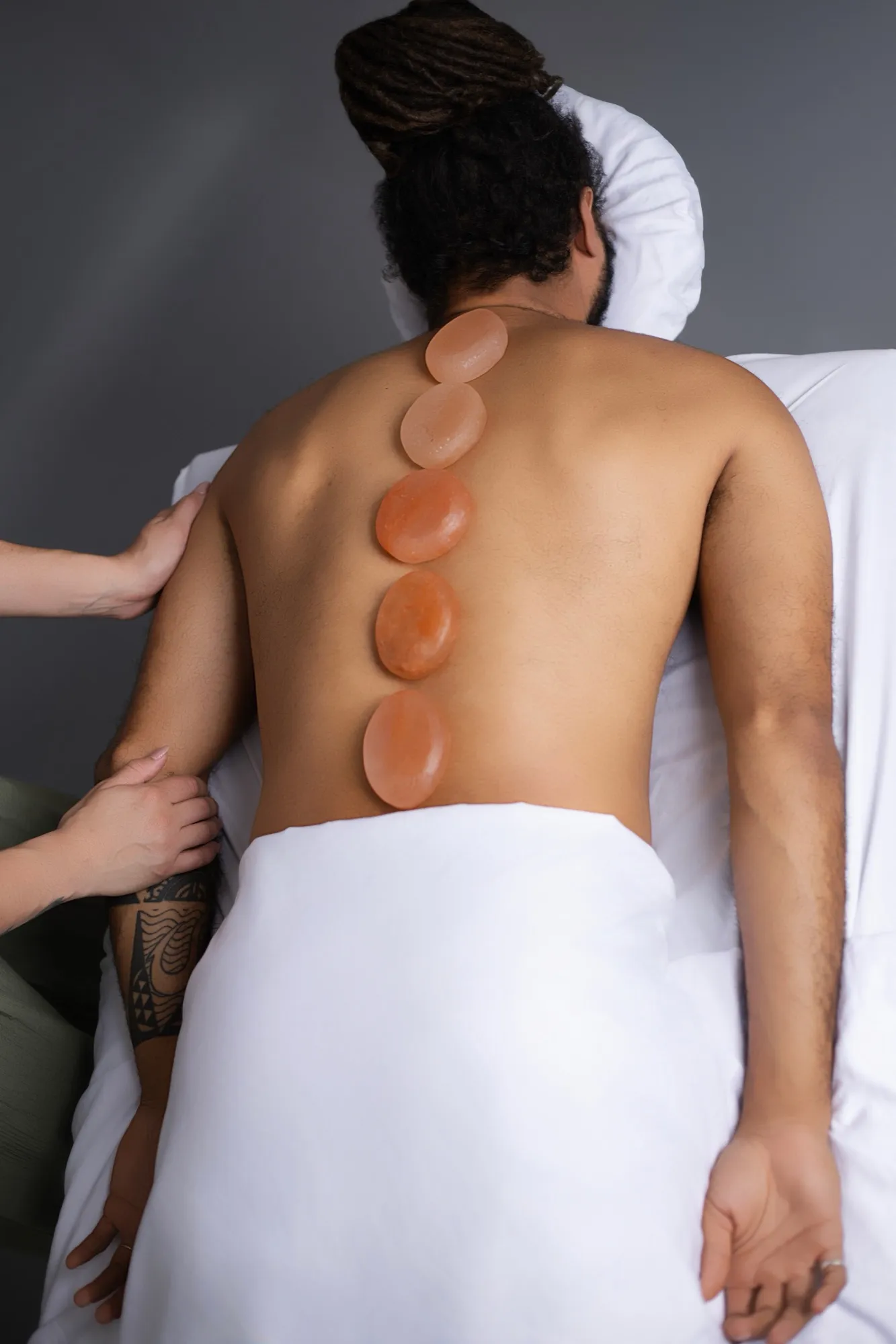 Warm Himalayan salt stones placed along a client’s spine
