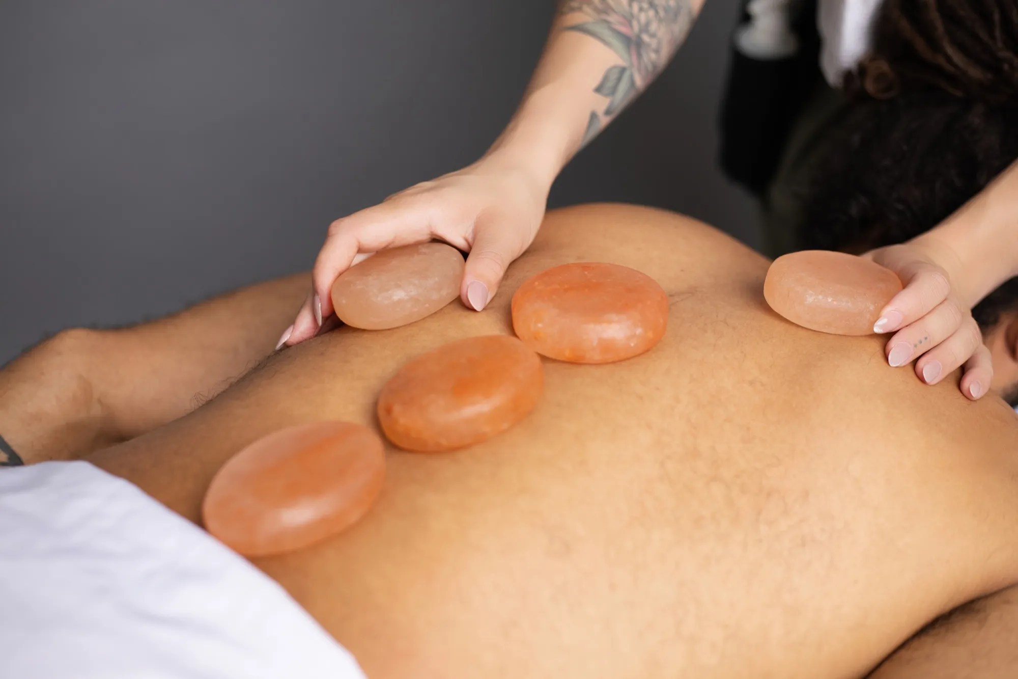 Warm Himalayan salt stones resting along a client's back